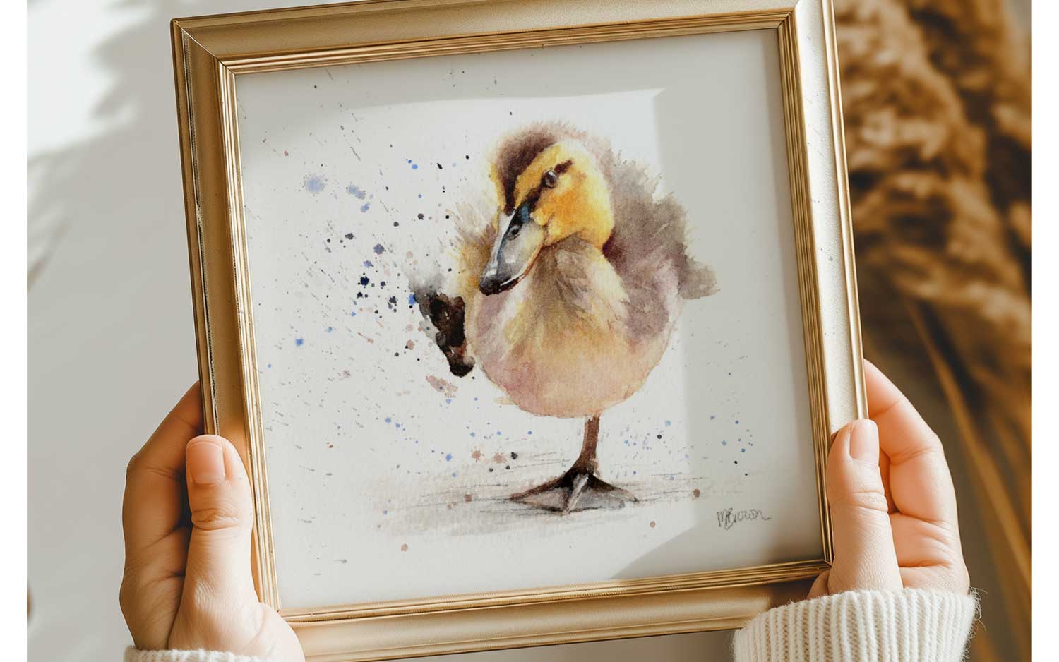 framed watercolour duckling print held by womans hands